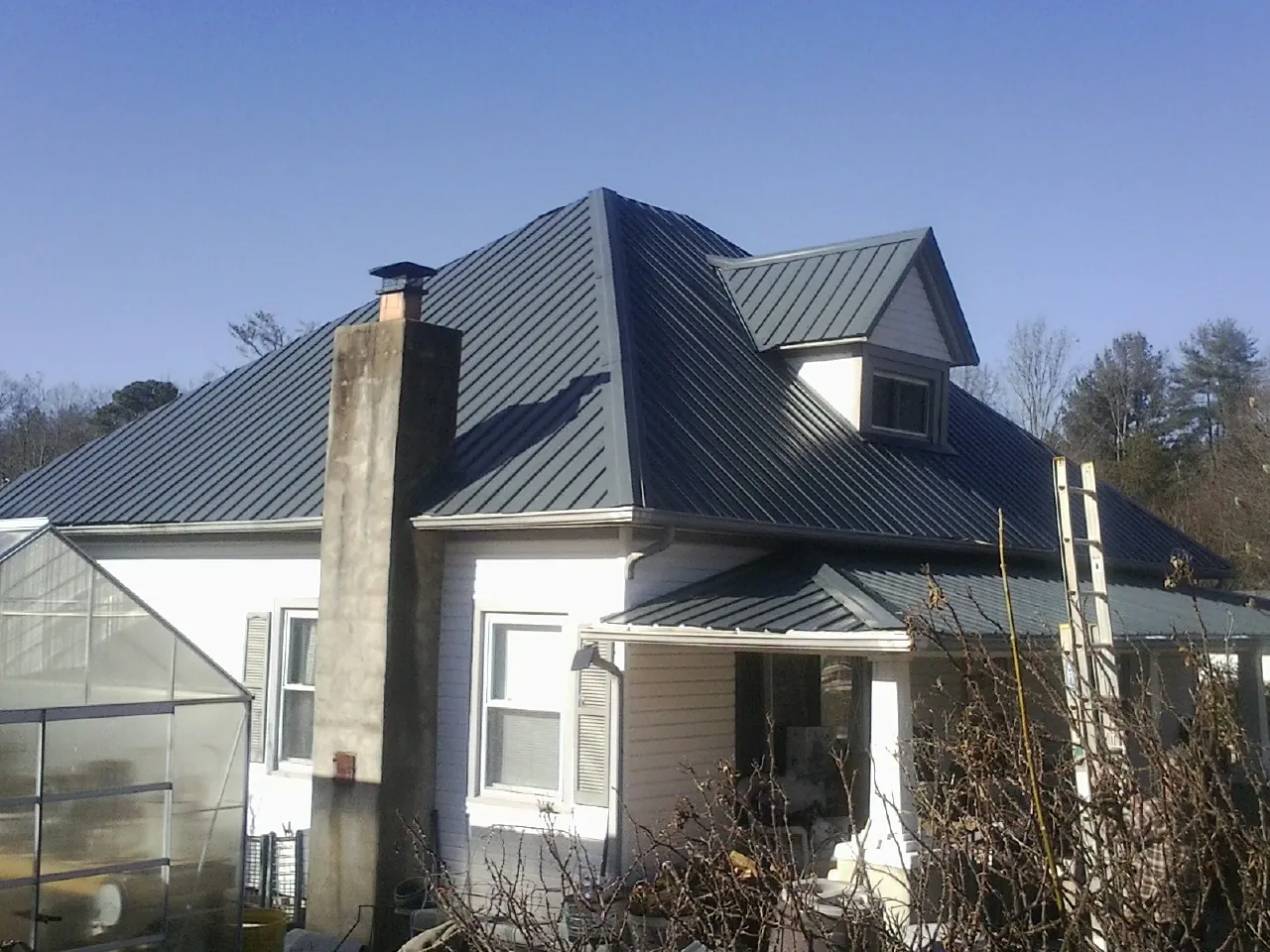 Dark blue standing seam metal roof on a white farmhouse with dormer — Slate & Tile Roof Repair by Roofing Brothers in Arispe