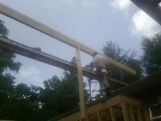 Carpenter setting a ridge beam over a new addition frame — Ice Dam Removal by Roofing Brothers in Arispe