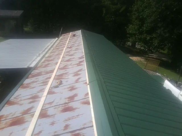 Old rusted panels beside newly installed green metal roofing — Wind Damage Roof Repair by Roofing Brothers in Arispe