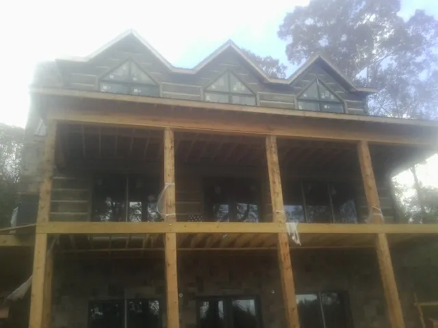 Dormers and porch framing on a large log home under construction — Roof Coating work by our crew in Arispe
