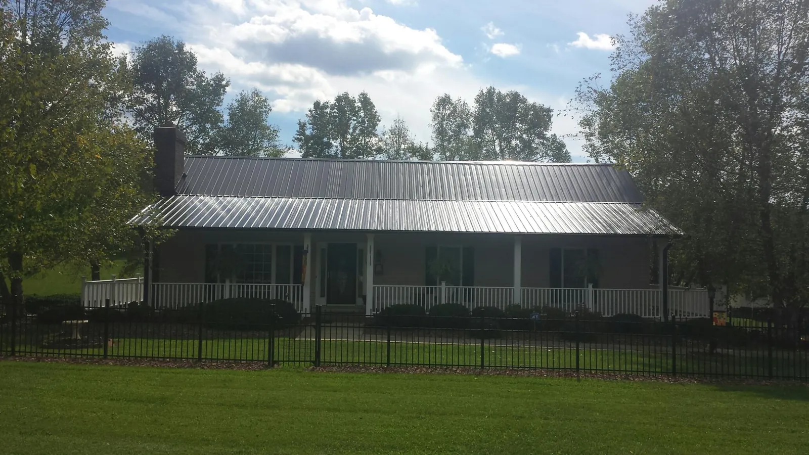 Gray metal roof on a brick ranch with a full width front porch — Gutter Guard Installation work by our crew in Arispe