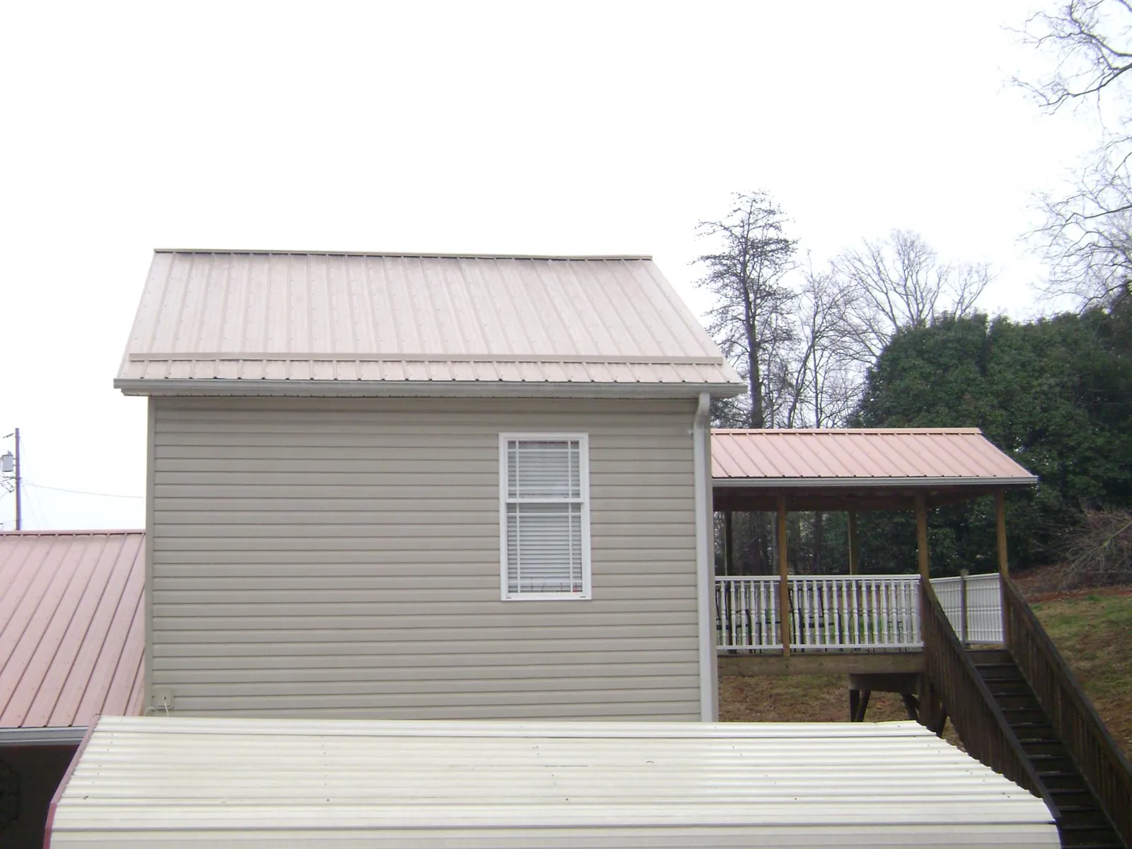 Tan metal roofs on a two story addition and attached porch, from a Roof Replacement job in Arispe