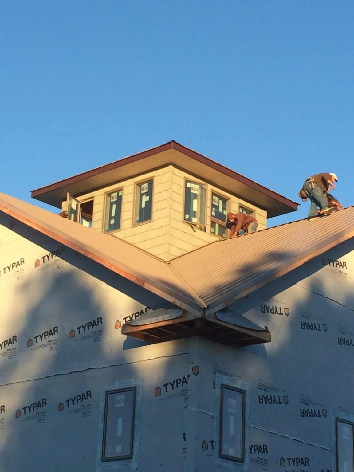 Roofers working around a rooftop cupola on a new metal roof at sunset — Roof Waterproofing in Arispe by Roofing Brothers